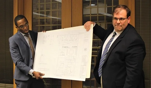 Trajah Buxton holding a large architectural floor plan with a colleague.